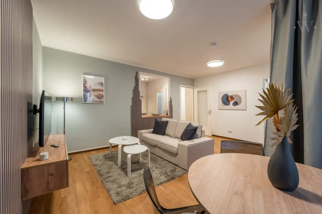 Cosy living room with light sofa, grey carpet, two round coffee tables, wall decoration and dining area with vase, in modern Scandinavian style