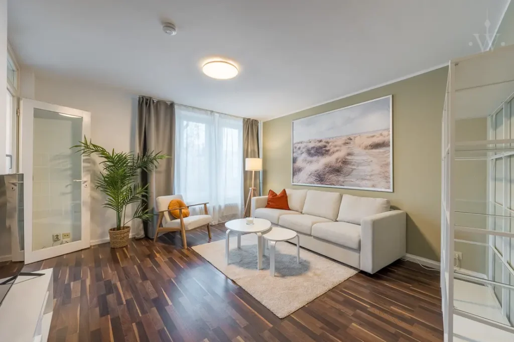 Living room with white sofa, carpet and plants.