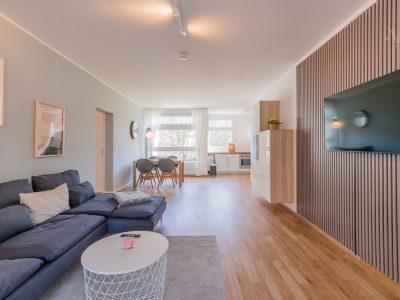 Apartment mit offenem Wohnraum, Couch und lichtdurchflutetem Fensterbereic