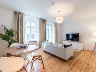 Helles Wohnzimmer mit zwei Sofas, Esstisch und Fernseher – stilvoll wohnen in Berlin