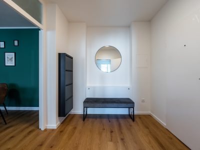 Minimalistischer Eingangsbereich mit Spiegel, Sitzbank und Holzboden im Apartment