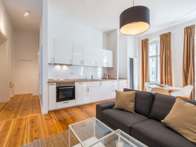 Moderne Wohnküche mit weißer Einbauküche, Sofa und stilvollem Holzfußboden