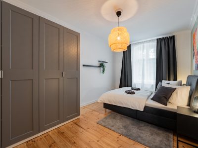 Schlafzimmer mit grauem Einbauschrank, Designerlampe und gemütlichem Doppelbett