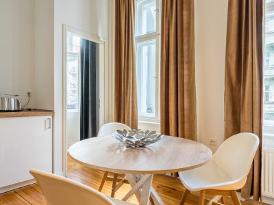 Heller Essbereich mit rundem Tisch, vier Stühlen und bodentiefen Fenstern