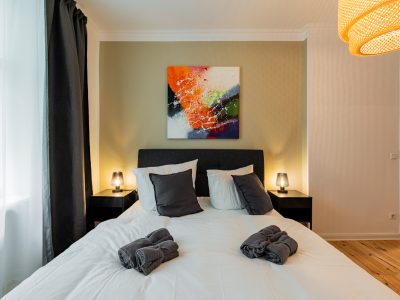 Stilvolles Schlafzimmer mit Kunst an der Wand, Nachttischen und einladender Beleuchtung